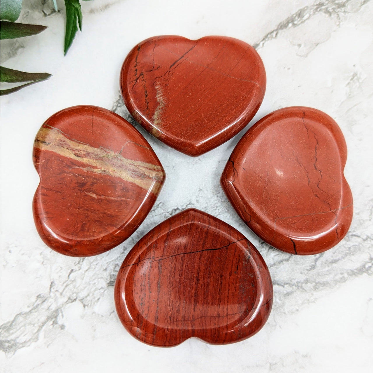 Three Red Jasper heart-shaped stones on marble surface for Red Jasper Thumb Stone #LV4301