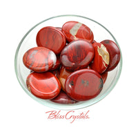 Thumbnail for Close-up of red jasper thumb stone in a bowl with black stones - Palm Stone #RJ39