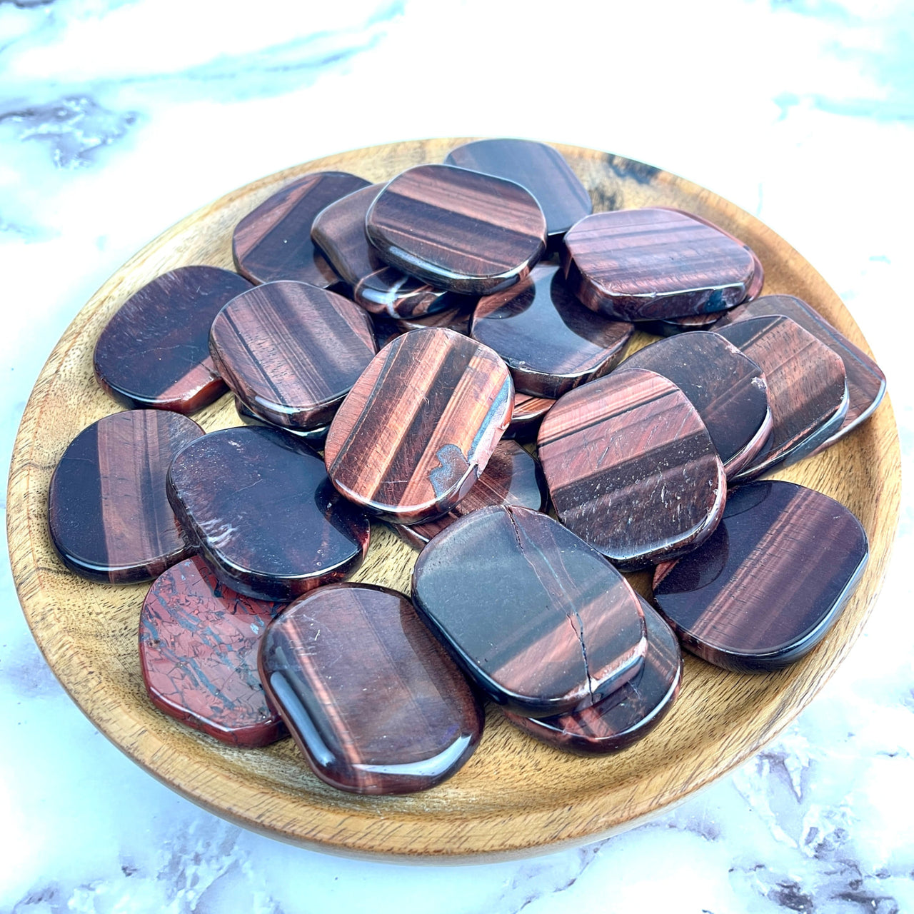 Wooden bowl filled with dark chocolates next to Red Tiger’s Eye Palmstone #LV1320