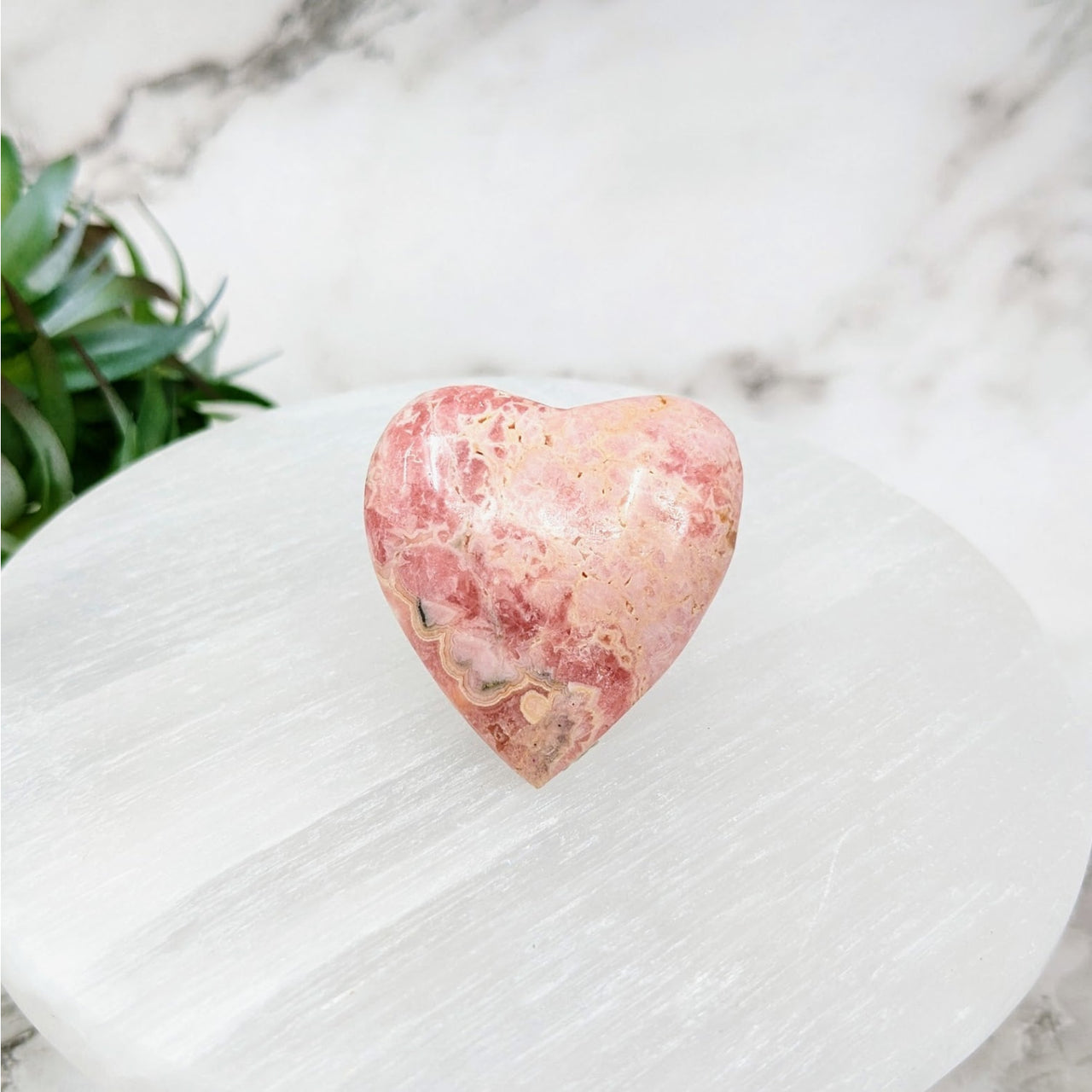 Rhodochrosite heart-shaped stone on white marble table for sale #LV4438