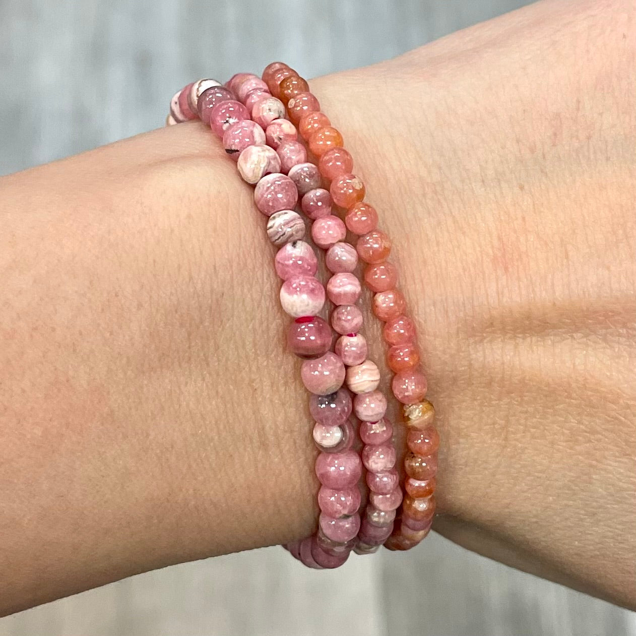 A woman’s arm adorned with pink and orange Rhodochrosite Bracelet (you pick size) #LV0050