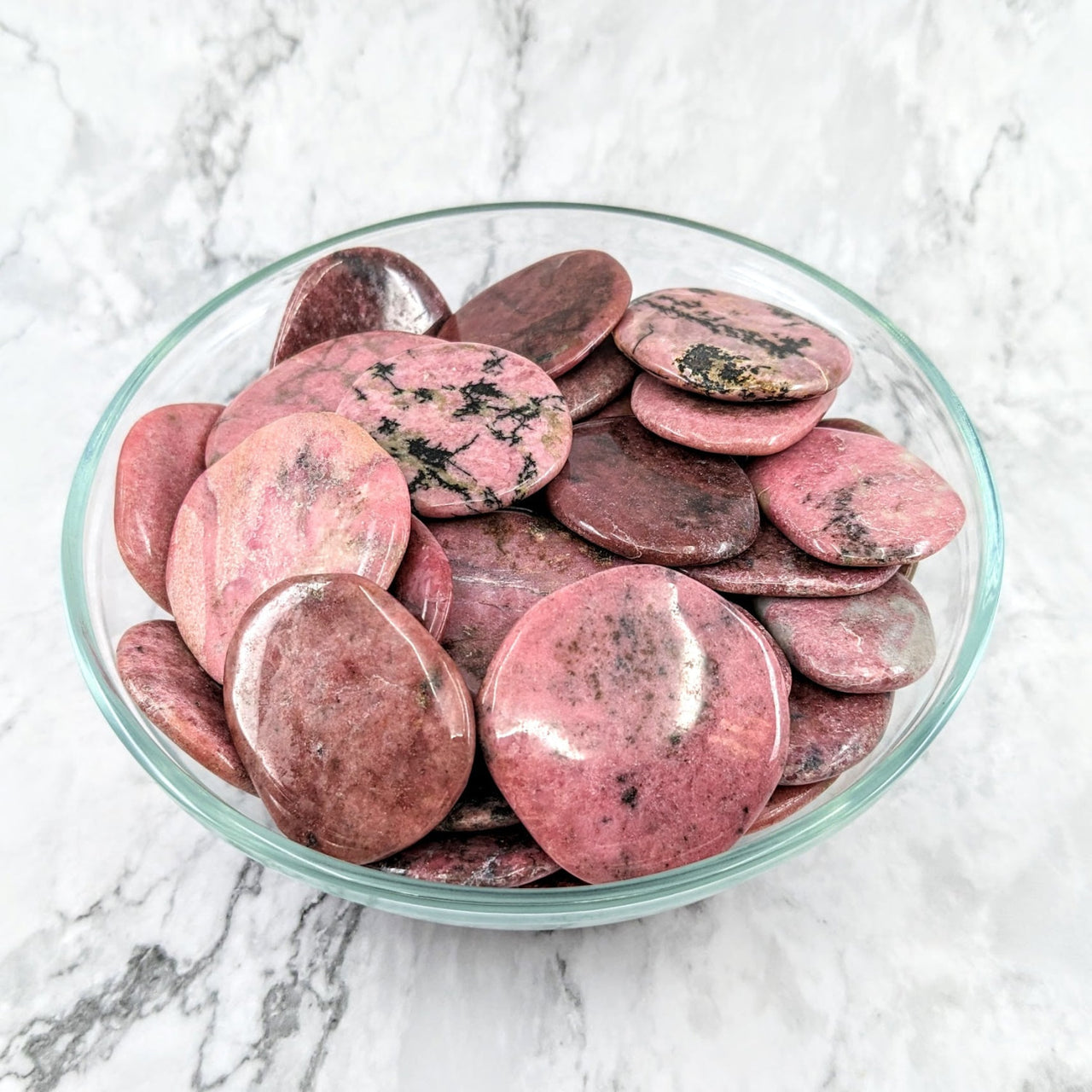 A bowl of red potatoes showcasing the beauty of Rhodonite Flat 1.7’ Palm Stone #LV1974