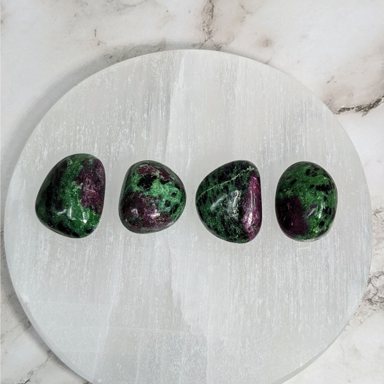 Three green and purple tumbled stones on white marble plate - Ruby Zoisite .9-1’ #LV4057