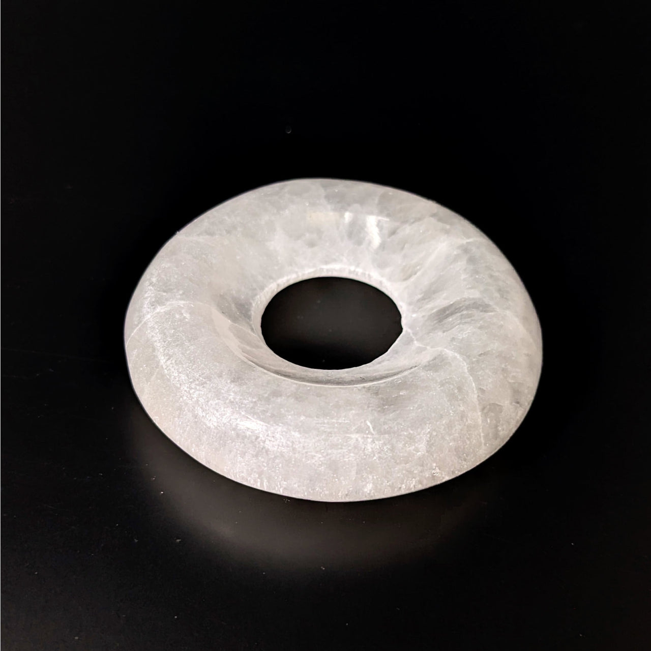 White quartz ring displayed on black surface with Selenite 2.4’ Sphere Stand #LV4134