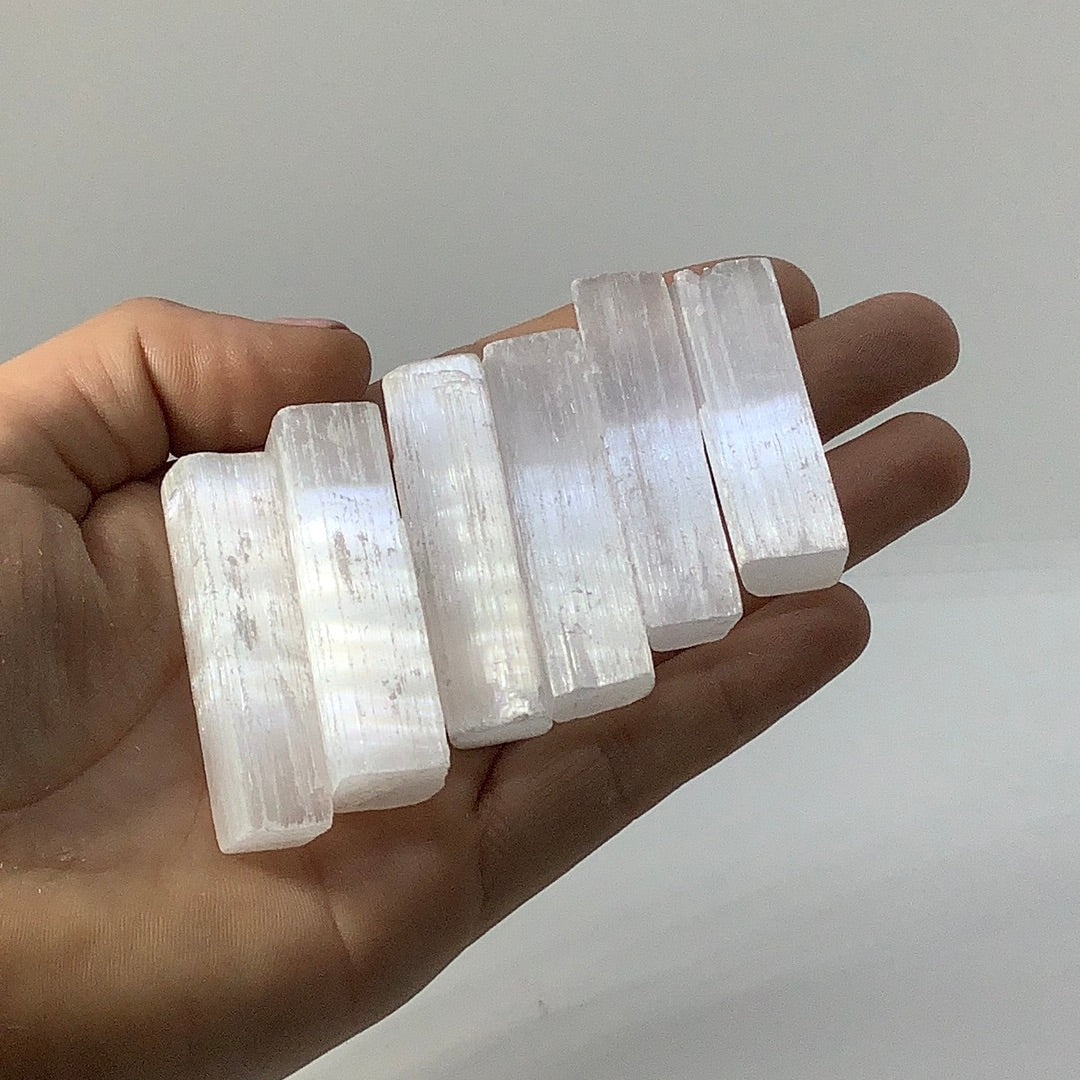 Hand holding Selenite Rough 2 Stick Parcel #JS013 with three quartz crystals