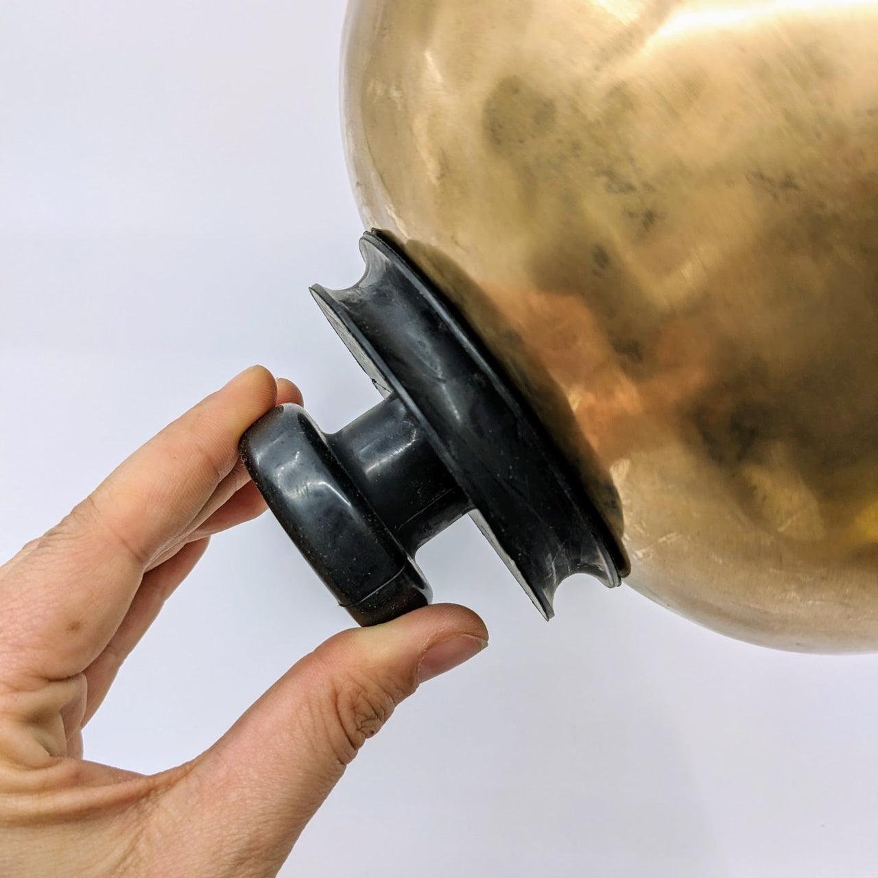 Hand holding brass Singing Bowl 3.2’ with black rubber suction handle #LV2901