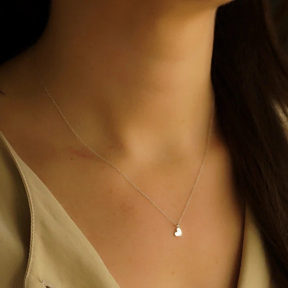 Woman wearing a gold necklace with a pearl accent from Sterling Silver Single Heart Necklace