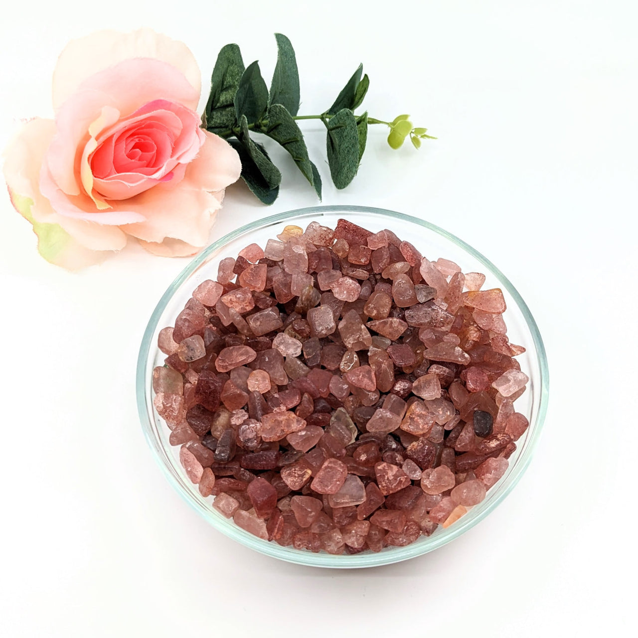 A bowl of pink crystals beside a rose: Strawberry Quartz Gravel Mini Chips 28g #LV3077