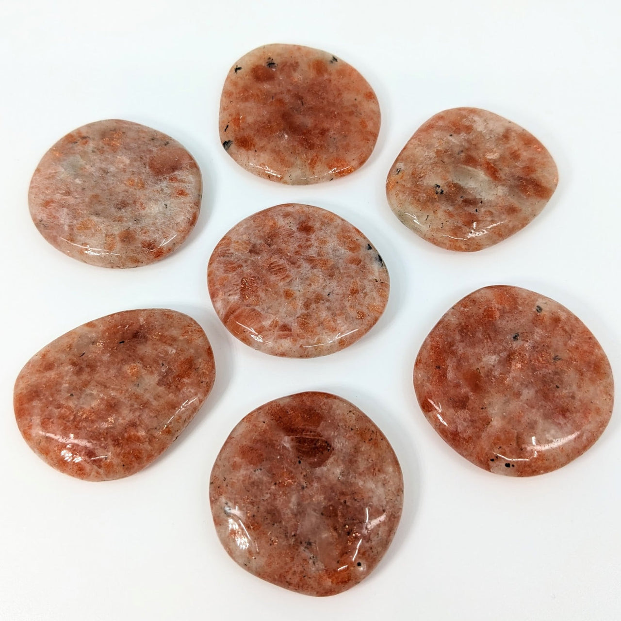 Palm stones: Six pieces of sausage on a white surface, Sunstone Flat #LV2447