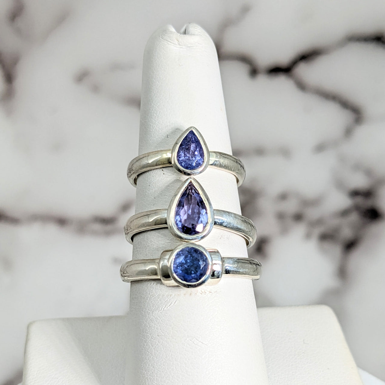 Blue and white sapphire gems displayed on a marble backdrop for Tanzanite Faceted SS Ring