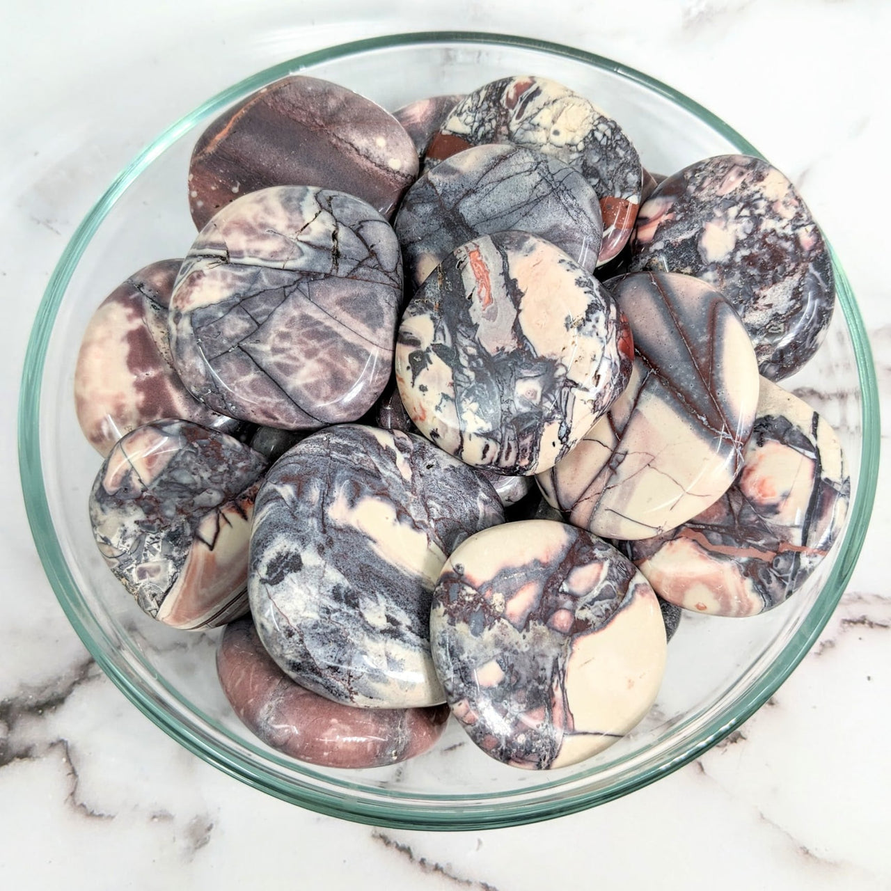 A bowl filled with marbles on a marble counter next to Tiffany Stone palm stones #LV2019