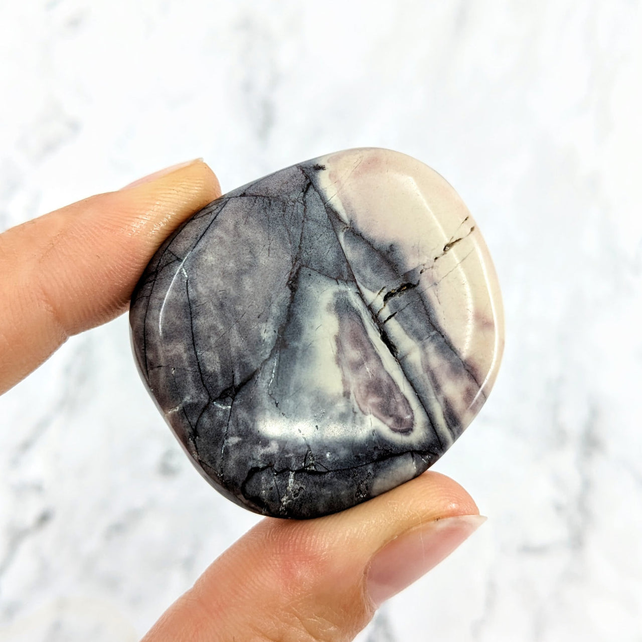 Hand holding a Tiffany Stone palm stone in black and white marble pattern #LV2019