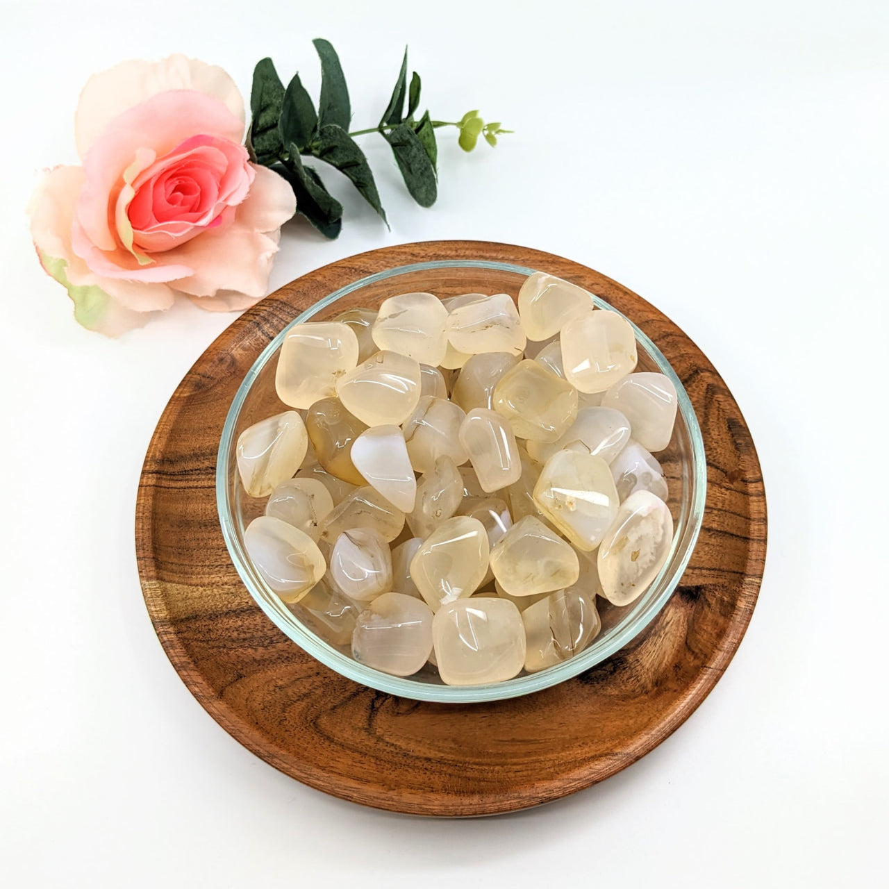 A bowl of sea glass with White Agate Tumbled Stones on a wooden plate, product #LV3071