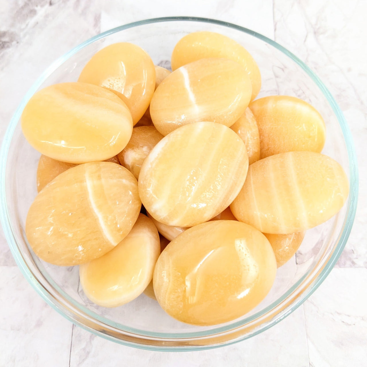 Peeled potatoes in a bowl displayed with Yellow Aragonite Pillow Palm Stone (#LV2268)