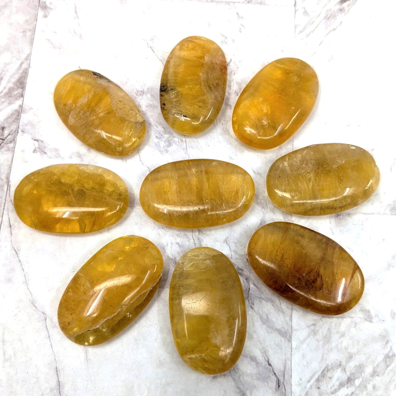 Close up of Yellow Fluorite Palm Stones (1.5’) #LV2277 on a marble surface